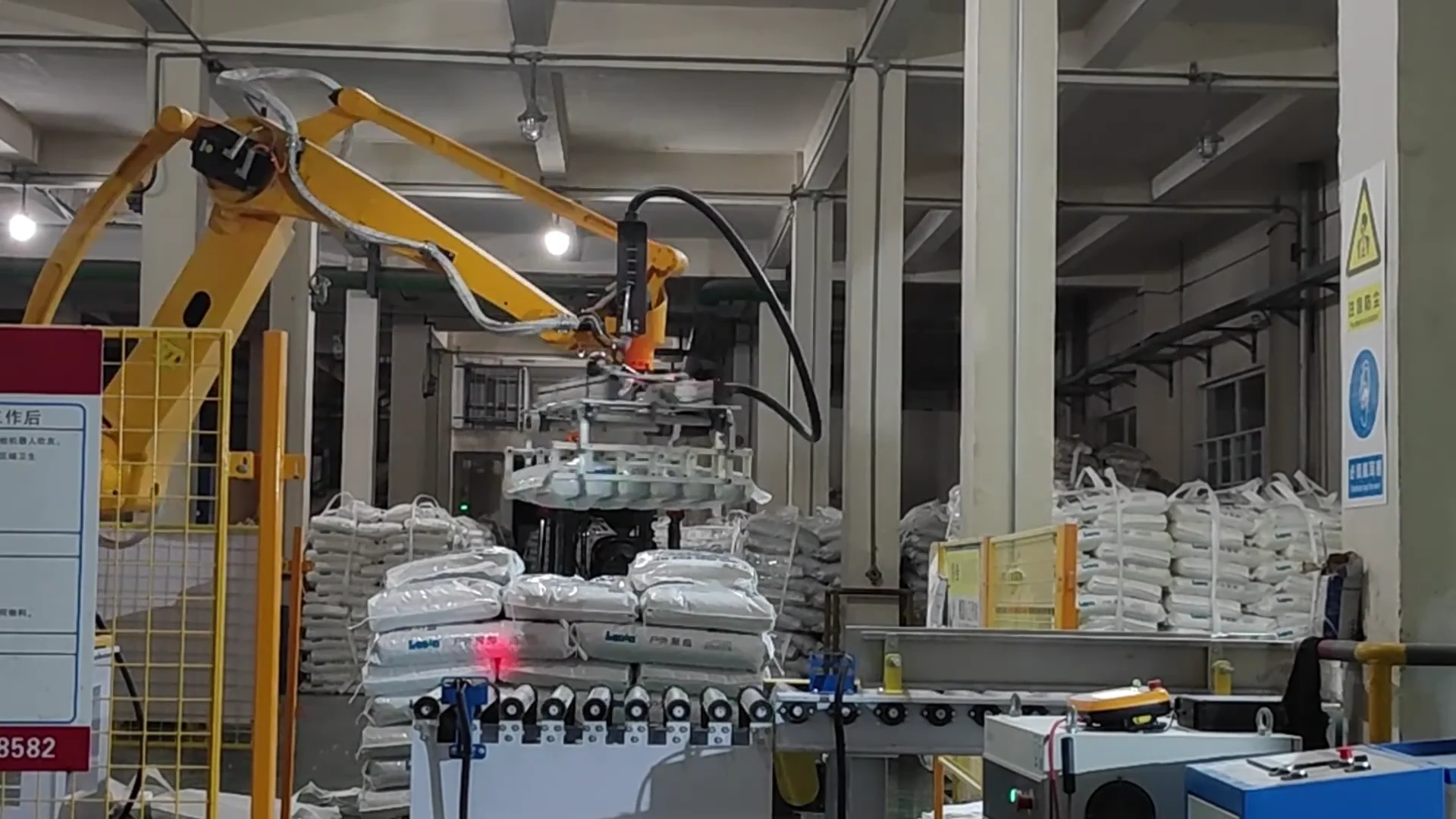 Robot with bag-handling gripper beside a conveyor and pallet at the customer site